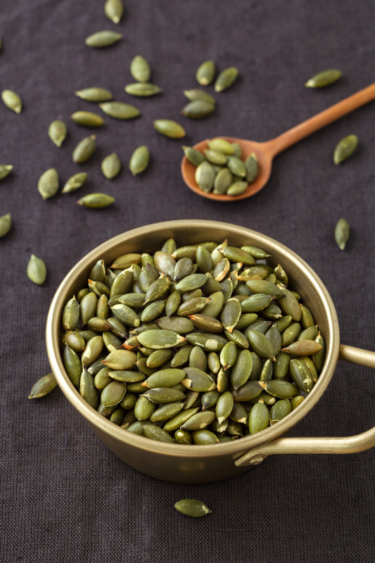 Pumpkin seeds in bowl on dark background